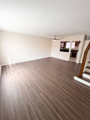 A room with wooden flooring and a ceiling fan.