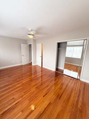 A room with wooden floors and a ceiling fan.