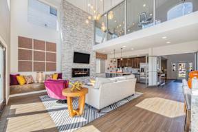 A modern living room with a stone fireplace and a white couch.