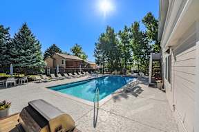 A sunny day at a poolside with a grill and lounge chairs.