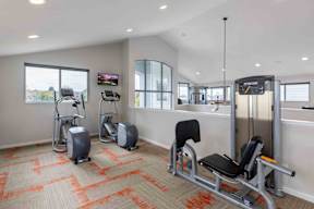 A gym with a variety of equipment including a rowing machine, a stationary bike, and a bench press.