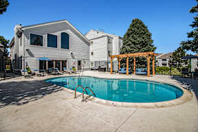 A pool in a backyard with a wooden pergola.