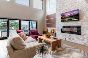 A living room with a couch, a chair, a coffee table, and a flat screen TV mounted on a brick wall.
