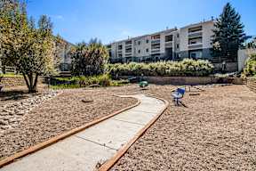 A playground with a slide in the middle of a sandy area.