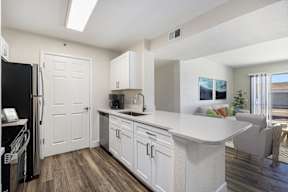 A kitchen with white cabinets and a black refrigerator.