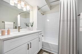 A bathroom with a white sink and a white shower curtain.
