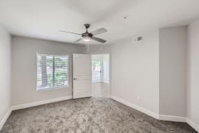 a bedroom with grey carpet and a ceiling fan