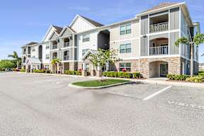 A large apartment complex with a parking lot in front.  at Mode at Melbourne Apartments, Melbourne, Florida