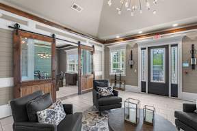 A living room with a black couch and a glass door.  at Mode at Melbourne Apartments, Melbourne, Florida