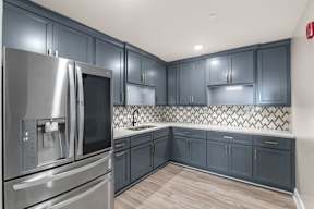 A kitchen with dark blue cabinets and a stainless steel refrigerator.  at Mode at Melbourne Apartments, Melbourne, Florida