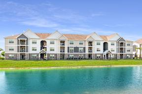 A large building with a lake in front of it at Mode at Melbourne Apartments, Melbourne, Florida