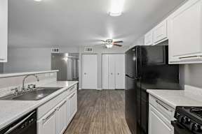 A kitchen with black appliances and white cabinets.