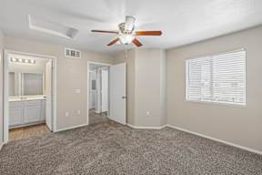 A room with a ceiling fan and carpeted floor.