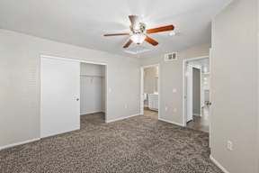A spacious room with a ceiling fan and carpeted floor.