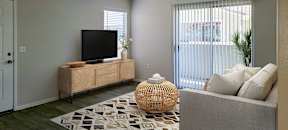 a living room with a tv on a stand in front of a sliding glass door at Silver Creek Apartments, Las Vegas, Nevada