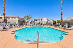 A swimming pool surrounded by palm trees and lounge chairs.