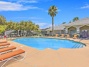 a swimming pool with chairs and a palm tree at Silver Creek Apartments, Las Vegas, NV, 89122