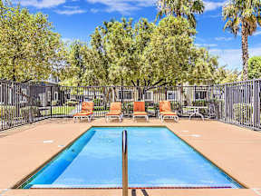 a swimming pool with chairs and a fence at Silver Creek Apartments, Las Vegas, 89122