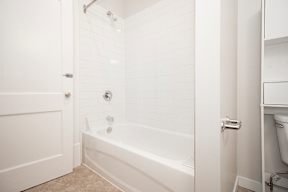 A white bathroom with a tub and toilet.