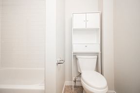 A white toilet sits next to a white bathtub in a bathroom.