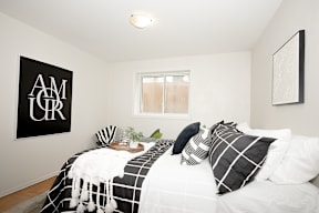 A bedroom with a bed, pillows, and a poster on the wall.