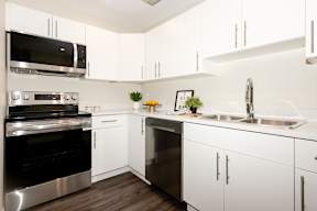 A modern kitchen with white cabinets and stainless steel appliances.