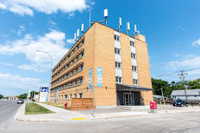 A large brick building with antennas on top and a blue sign in front.