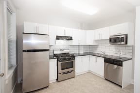 a kitchen with stainless steel appliances and white cabinets at 883 Grosvenor Apartments Winnipeg