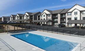 a swimming pool with a fence in front of an apartment complex