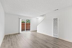 A room with a white ceiling, wooden floors, and a window with a view of a backyard at Stony Creek Apartments, Santa Rosa
