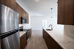 A modern kitchen with a stainless steel refrigerator and wooden cabinets.