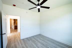 A room with a ceiling fan and a doorway leading to another room.