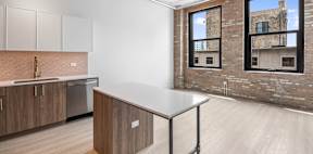 A kitchen with a brick wall and a window.