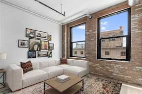 A white couch with a coffee table in front of it and pictures on the wall.