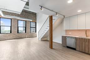A kitchen with a wooden floor and a staircase.