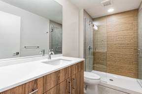 A modern bathroom with a white sink and wooden cabinets.