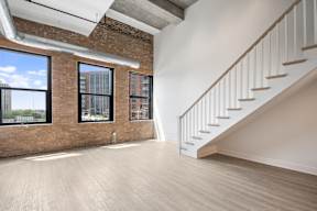 A room with a staircase and a window overlooking a cityscape.