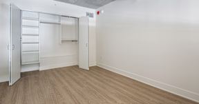 A white room with a wooden floor and a white closet with shelves.