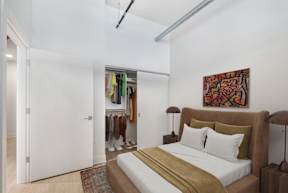 A bedroom with a bed, a lamp, and a painting on the wall.