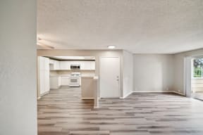 an empty living room and kitchen with wood flooring