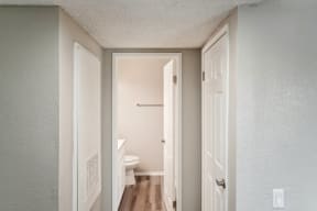 an empty hallway with a door open to a bathroom with a toilet