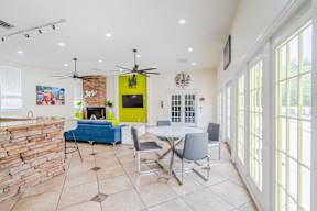 A living room with a brick fireplace and a dining table with chairs.