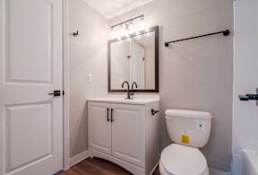 A white toilet with a yellow sticker on it is in a bathroom with a white cabinet and a mirror above it.