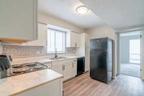 A kitchen with a black refrigerator and white cabinets.