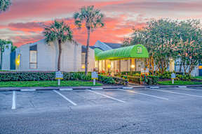 A parking lot in front of a building with a green awning and the number 59 on it.