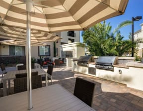 a patio with a grill and a table with chairs