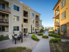 a courtyard with tables and chairs in front of an apartment building