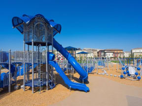 a playground with a large blue slide in front of a building