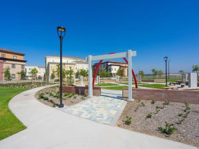 a walkway with a white arch in the middle and buildings in the background