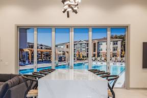 A modern dining room with a view of a pool and apartment buildings.